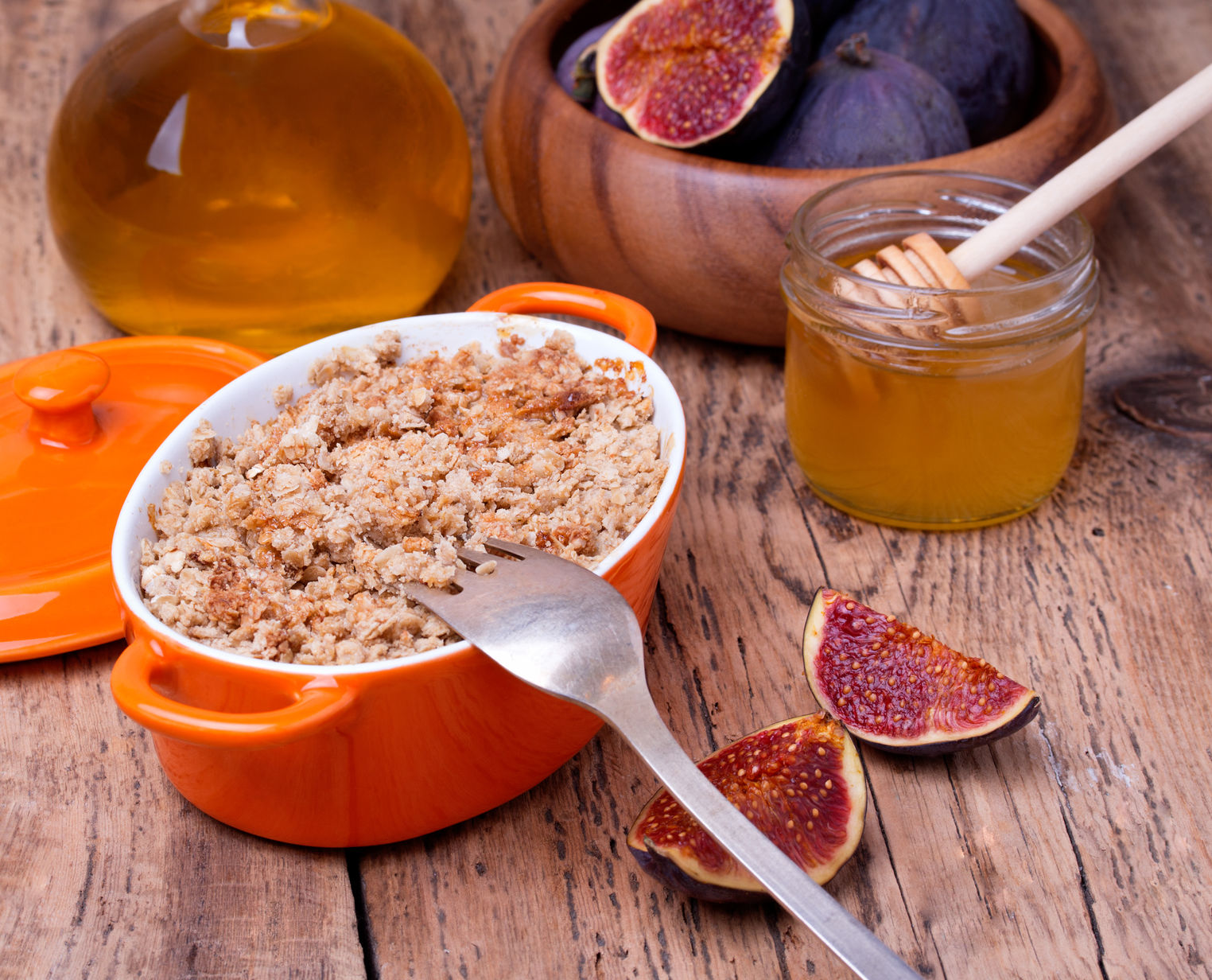 32337930 - apple and figs crumble in orange ceramic dish with honey on wooden background