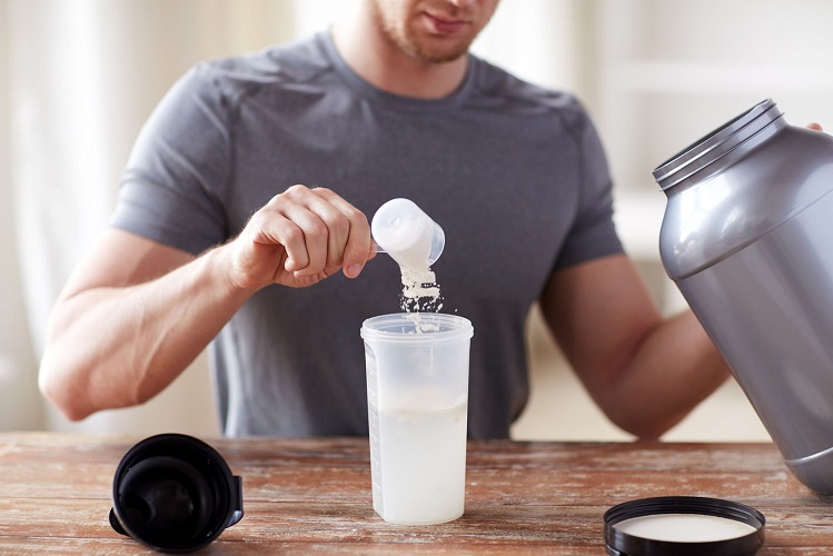 53634760 - sport, fitness, healthy lifestyle and people concept - close up of man with jar and bottle preparing protein shake